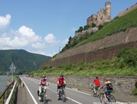 Radler auf dem Rhein-Radweg radeln bei Rüdesheim an einer Burgruine vorbei